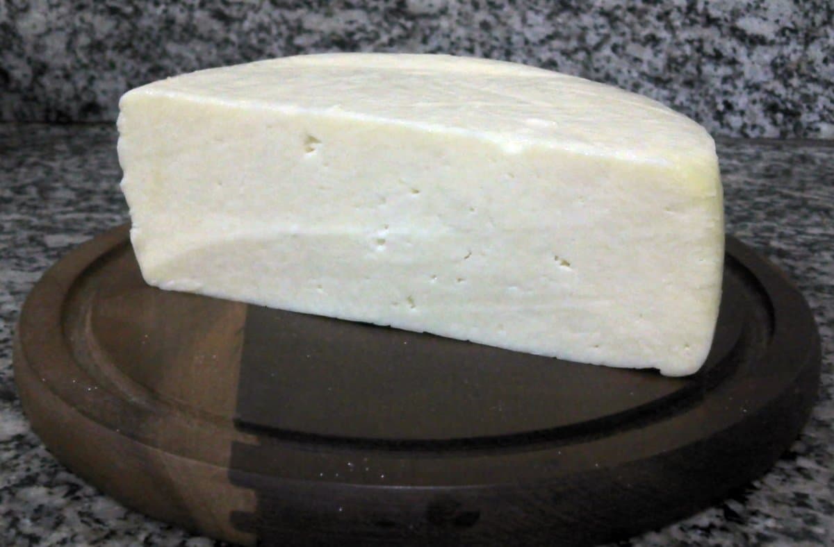 Peça de queijo coalho branco sobre tábua de madeira
