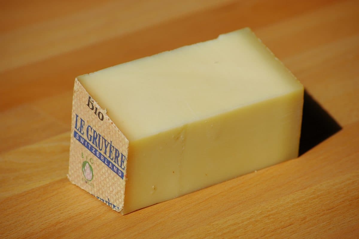 Pedaço de queijo Gruyère suíço com a casca original da forma, sobre superfície de madeira
