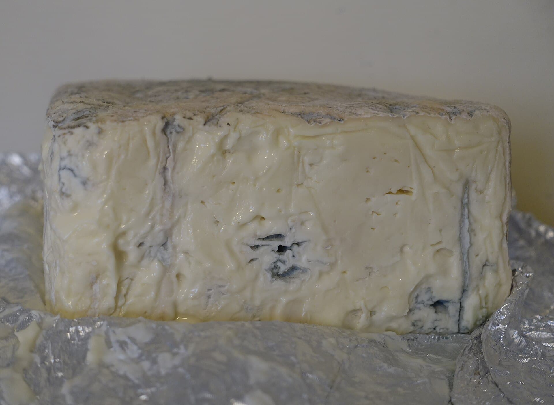 Bloco de queijo gorgonzola cremoso com veios azuis, sobre papel alumínio